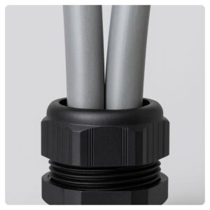 Close-up of a plastic cable gland with two grey 25mm² PVC meter tails entering a metal consumer unit.